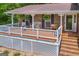 Charming front porch with seating, ferns, white railings, and brick columns and steps at 6023 Highway 20 S, Covington, GA 30016