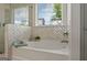 Bright bathroom featuring a soaking tub with white herringbone tile at 5350 Woodline View Cir, Hoschton, GA 30548