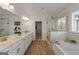 Bright bathroom featuring double vanity, soaking tub, and separate glass-enclosed shower with stylish tile at 5350 Woodline View Cir, Hoschton, GA 30548