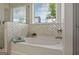 Relaxing tub area featuring stylish chevron tile, garden tub and natural light from the window at 5350 Woodline View Cir, Hoschton, GA 30548