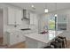 Well-designed kitchen featuring white cabinetry, a stainless steel range hood, and a breakfast bar at 5350 Woodline View Cir, Hoschton, GA 30548