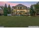 Evening view of the backyard featuring a well-lit home exterior and a large grassy area at 719 Bethpage Dr, Mcdonough, GA 30253
