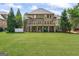 Expansive backyard view featuring the home's exterior, a well-maintained lawn, and a covered patio at 719 Bethpage Dr, Mcdonough, GA 30253
