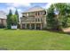 Large, well-manicured backyard view of the home's exterior with a covered patio and lush greenery at 719 Bethpage Dr, Mcdonough, GA 30253