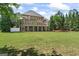 Spacious backyard view with lush lawn and mature trees, showcasing the home's exterior and covered patio at 719 Bethpage Dr, Mcdonough, GA 30253