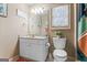 Bright bathroom featuring a white vanity, toilet, vanity lighting and window with decorative accents at 719 Bethpage Dr, Mcdonough, GA 30253