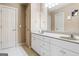 Bathroom features double sink vanity with white cabinets, white tiled floors, and framed mirror at 719 Bethpage Dr, Mcdonough, GA 30253