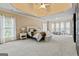 Bright and airy main bedroom with carpeted floor, ceiling fan and seating area by the window at 719 Bethpage Dr, Mcdonough, GA 30253