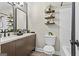 This bathroom features a double sink, wood cabinets, wood shelves, a white toilet, and a shower-tub combo at 2687 Fairfield Sw Dr, Marietta, GA 30064