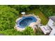 Aerial view of a covered in-ground pool surrounded by a patio, table with umbrella, chairs and lush greenery at 2810 Jodeco Ter, Jonesboro, GA 30236