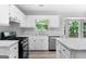 Bright kitchen featuring white cabinets, marble countertops, stainless steel appliances, and ample natural light at 11203 Hemlock Rd, Hampton, GA 30228