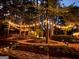 Backyard with string lights, landscape lighting, mulch beds, and stone path at 120 Tall Pine Dr, Fayetteville, GA 30214