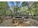 Beautiful backyard with a stone fire pit surrounded by mature trees and outdoor seating, perfect for enjoying nature at 120 Tall Pine Dr, Fayetteville, GA 30214