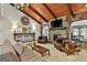 Comfortable living room boasts wood ceilings, a stone fireplace, and views into the kitchen area at 120 Tall Pine Dr, Fayetteville, GA 30214