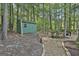 Green shed in a wooded lot featuring a pea gravel path with landscape lighting and benches at 120 Tall Pine Dr, Fayetteville, GA 30214