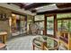 Relaxing sunroom with brick walls, multiple glass doors, and decorative peacock chair with views to an outdoor deck at 120 Tall Pine Dr, Fayetteville, GA 30214