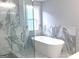 Elegant bathroom featuring a glass shower and freestanding tub with marble style tile and natural light at 3189 Jackson, Hapeville, GA 30354