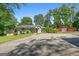 Charming single-story home with a well-manicured front yard, mature trees, and a red barn in the background at 312 Flat Shoals Church Rd, Stockbridge, GA 30281