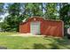 Red garage with white doors and a concrete pad with grassy yard and mature trees at 312 Flat Shoals Church Rd, Stockbridge, GA 30281