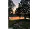 Serene lakefront view with a landscaped garden, trees, and vibrant sunset colors at 312 Flat Shoals Church Rd, Stockbridge, GA 30281