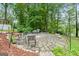 Beautiful outdoor patio with stone pavers, an outdoor grilling area, and views of the lush, wooded backyard at 312 Flat Shoals Church Rd, Stockbridge, GA 30281
