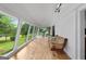 Bright sunroom with hardwood floors, white brick walls, and a large bank of windows overlooking the landscaped yard at 312 Flat Shoals Church Rd, Stockbridge, GA 30281
