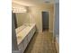 Bathroom with dual sinks, white cabinets, tiled floors, and a well-lit mirror at 590 Dot Dr, Atlanta, GA 30349