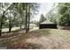 Picturesque backyard featuring mature trees, a charming storage building, and lush green grass at 8394 Banks Mill Rd, Douglasville, GA 30135