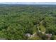 Aerial shot of verdant woodland, a house, and a barn-like building, all accessible via a private gravel road at 6605 Old White Mill Rd, Fairburn, GA 30213