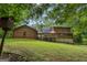 Expansive backyard view showcasing the log-sided home, a deck, and a serene, tree-lined landscape at 6605 Old White Mill Rd, Fairburn, GA 30213