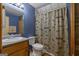 Bathroom with blue walls, wooden vanity, and decorative shower curtain at 6605 Old White Mill Rd, Fairburn, GA 30213