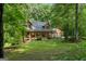 Front exterior view of the log cabin home showing covered front porch and mature trees at 6605 Old White Mill Rd, Fairburn, GA 30213