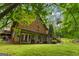 Charming view of the log-sided home's exterior, a well-manicured lawn, and lush greenery at 6605 Old White Mill Rd, Fairburn, GA 30213