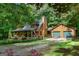 Charming log home with a covered front porch and an attached two-car garage, surrounded by lush greenery and mature trees at 6605 Old White Mill Rd, Fairburn, GA 30213