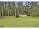 This wide lot features a detached garage and an expansive lawn surrounded by mature trees, enclosed by a chain-link fence at 150 Whitney Way, Fayetteville, GA 30214