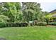 A sprawling backyard features a large lawn, mature trees, a playset, and manicured hedges with a glimpse of the home's exterior at 1486 Maple Ridge Dr, Suwanee, GA 30024