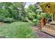 Lush backyard featuring manicured lawn, deck, garden beds, and natural landscaping at 1486 Maple Ridge Dr, Suwanee, GA 30024