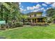 An expansive backyard featuring a spacious lawn, mature trees, a deck with potted plants, and a charming two-story home at 1486 Maple Ridge Dr, Suwanee, GA 30024