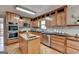 Well-lit kitchen features light wood cabinets, island with sink, stainless appliances, and light tile backsplash at 1486 Maple Ridge Dr, Suwanee, GA 30024