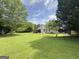 Spacious backyard with lush green lawn, mature trees, and a charming covered patio, perfect for outdoor gatherings at 105 Carols Ln, Locust Grove, GA 30248