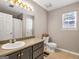 Bright bathroom features tiled floor, a commode, and a sink with a large mirror at 105 Carols Ln, Locust Grove, GA 30248