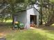 An outdoor shed containing some items with a John Deere tractor parked outside at 105 Carols Ln, Locust Grove, GA 30248