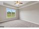 Spacious bedroom with large window letting in natural light, neutral carpet, and a ceiling fan at 123 Oak Road, Locust Grove, GA 30248