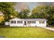 Home with a green lawn and neutral exterior featuring black shutters and a small storage shed at 361 N Dogwood Ave, Social Circle, GA 30025