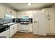 Well-lit kitchen with white cabinets, black countertops, and modern appliances, including a white refrigerator and stove at 142 Kylee Ct, Villa Rica, GA 30180