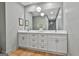 Bright bathroom featuring double sinks, large mirror, white cabinets, and wood floors at 502 Pine Cir, Peachtree City, GA 30269