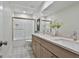 Bright bathroom featuring double vanity with quartz countertop, decorative floor tiles, and bathtub with glass enclosure at 502 Pine Cir, Peachtree City, GA 30269