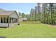 Back view of a white home featuring a well-maintained backyard and a screened-in porch at 82 Airmont Dr, Sharpsburg, GA 30277
