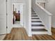 Entry hall and staircase with wood floors and white risers leading to a bedroom with a four-poster bed at 82 Airmont Dr, Sharpsburg, GA 30277