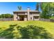 Large backyard with lush green grass, mature trees, and covered patio at 105 Turnberry Trce, Sharpsburg, GA 30277